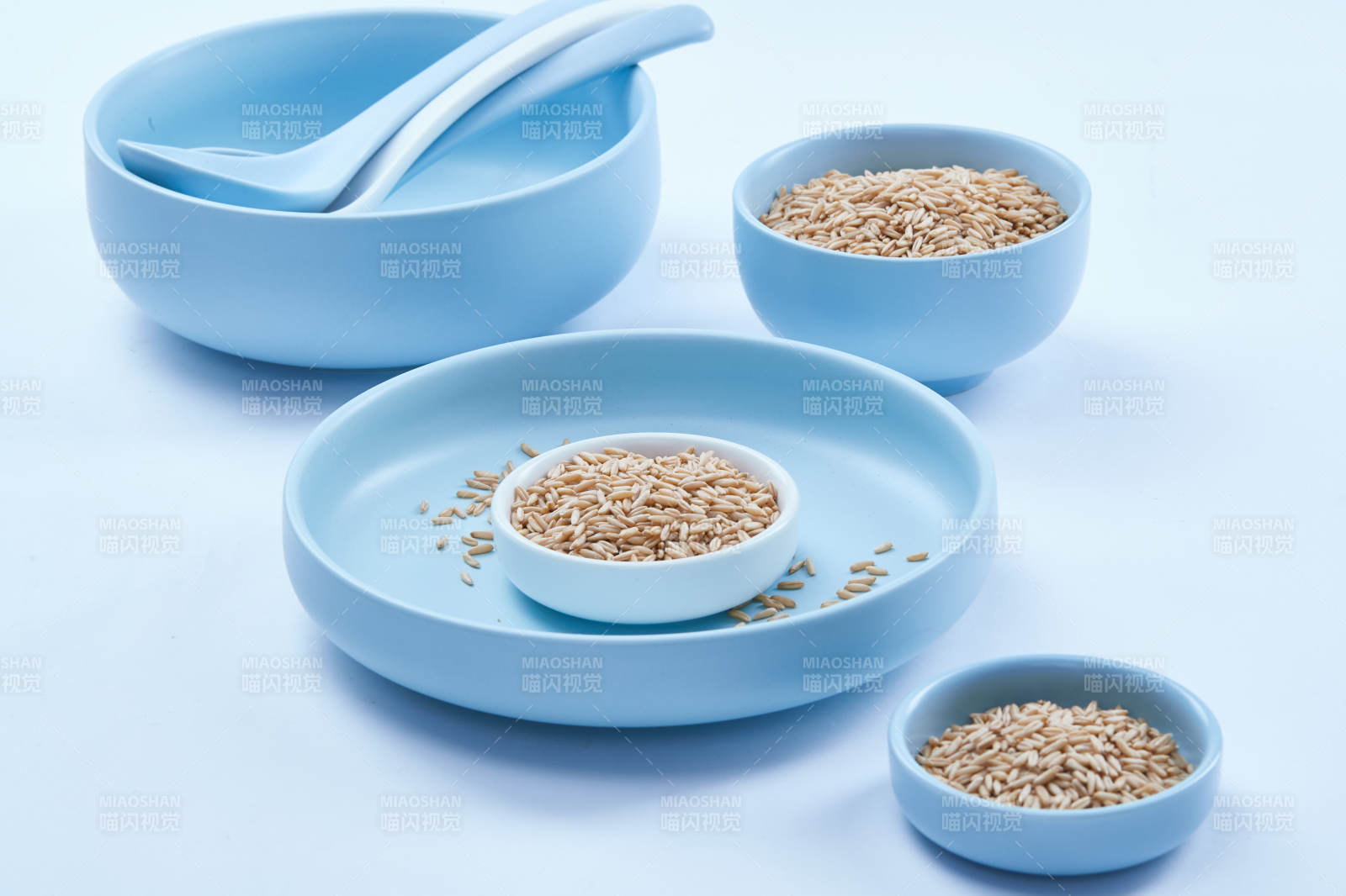 白色纸背景上的青釉瓷餐具及木质餐具装的燕麦米