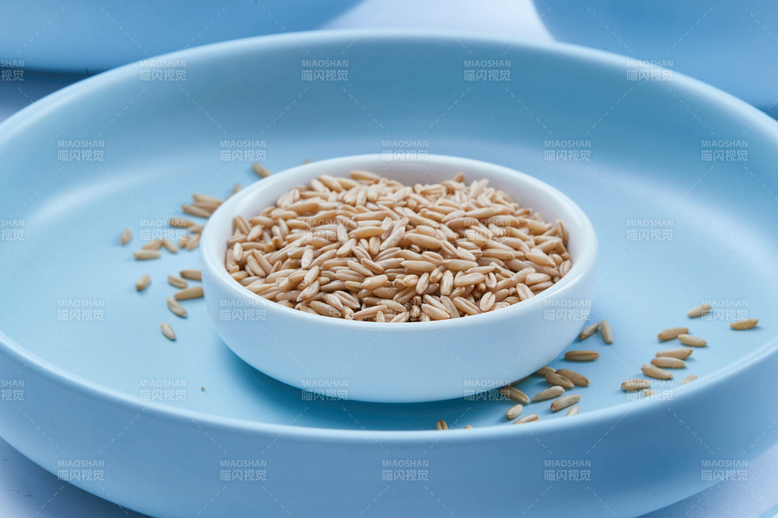 白色纸背景上的青釉瓷餐具及木质餐具装的燕麦米