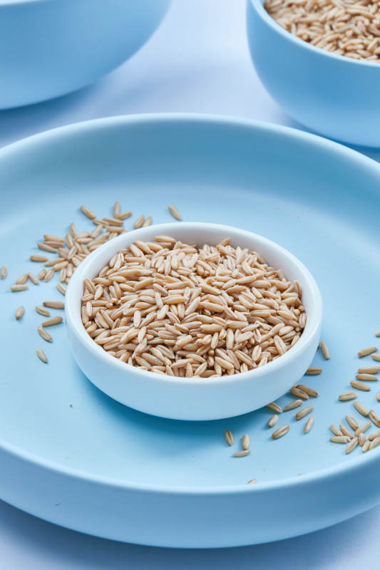 白色纸背景上的青釉瓷餐具及木质餐具装的燕麦米