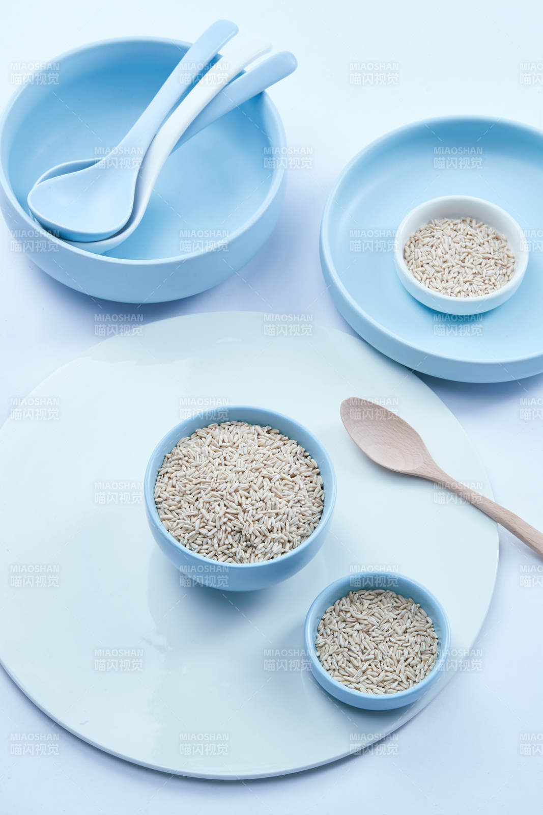 白色纸背景上的青釉瓷餐具及木质餐具装的燕麦米