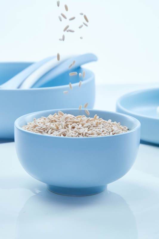 白色纸背景上的青釉瓷餐具及木质餐具装的燕麦米