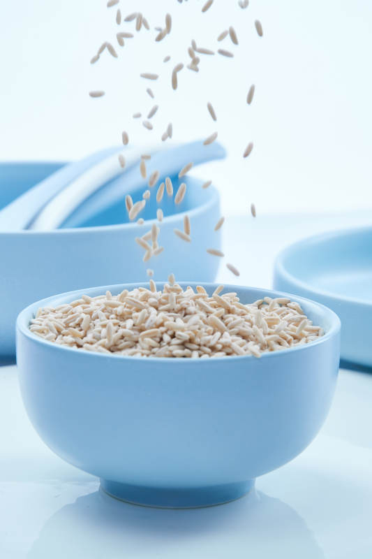 白色纸背景上的青釉瓷餐具及木质餐具装的燕麦米