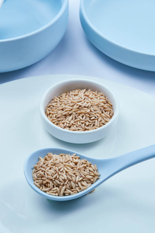 白色纸背景上的青釉瓷餐具及木质餐具装的燕麦米