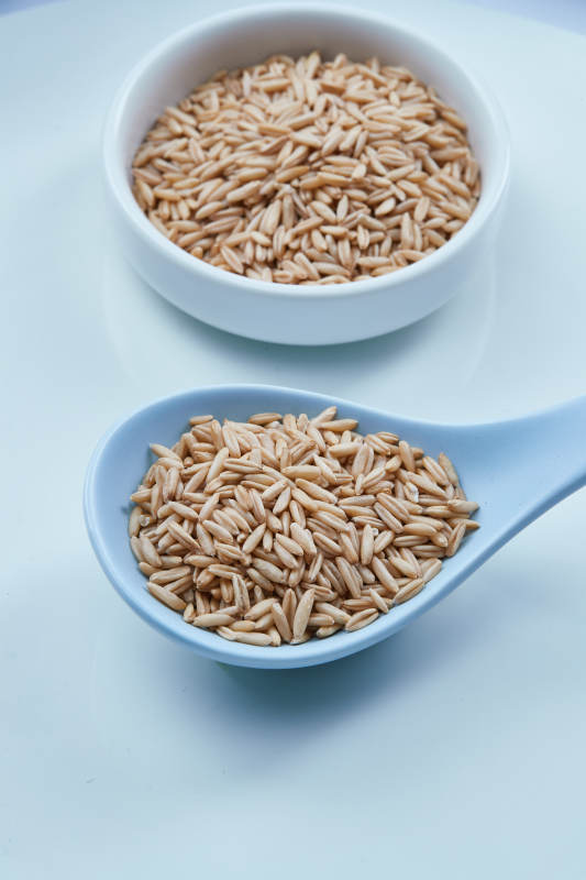 白色纸背景上的青釉瓷餐具及木质餐具装的燕麦米