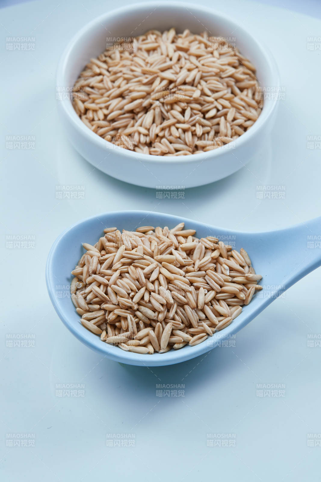 白色纸背景上的青釉瓷餐具及木质餐具装的燕麦米