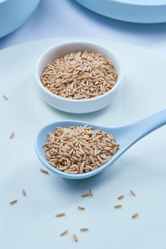 白色纸背景上的青釉瓷餐具及木质餐具装的燕麦米