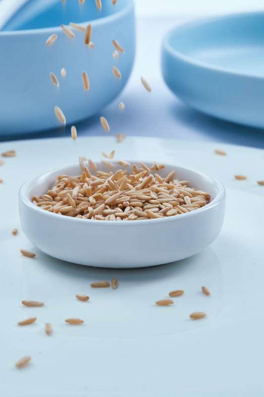 白色纸背景上的青釉瓷餐具及木质餐具装的燕麦米