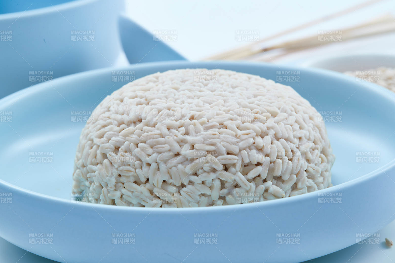 白色纸背景上的青釉瓷餐具及木质餐具装的燕麦米