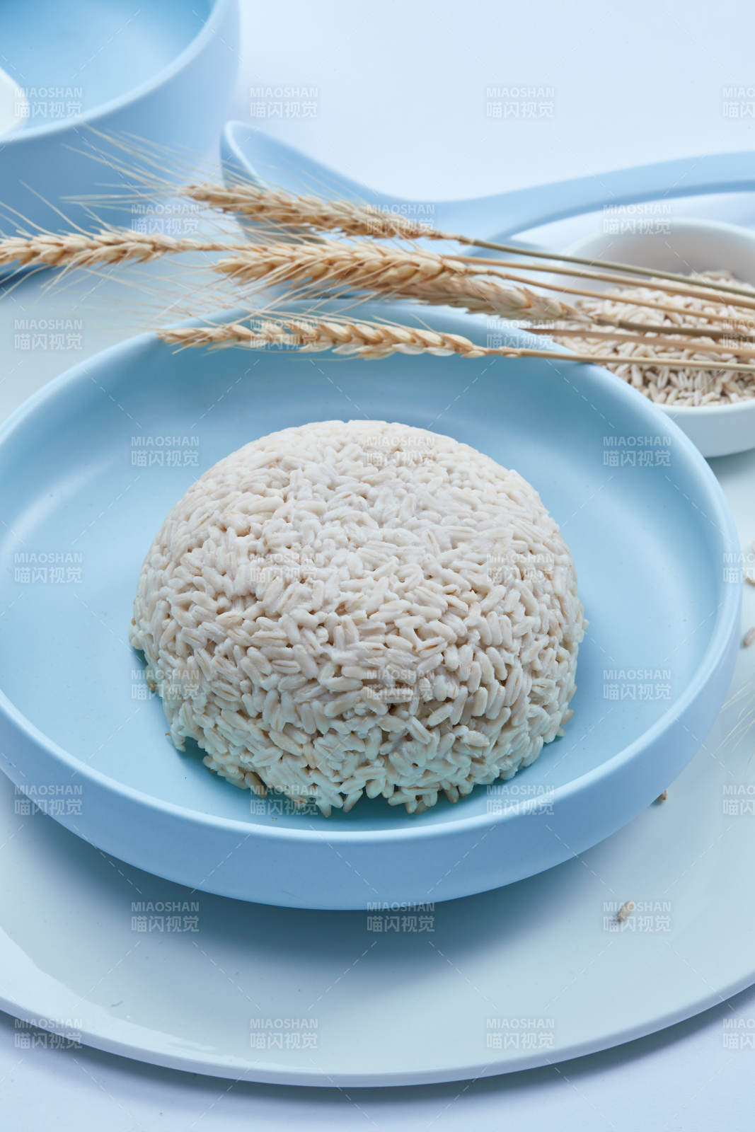 白色纸背景上的青釉瓷餐具及木质餐具装的燕麦米