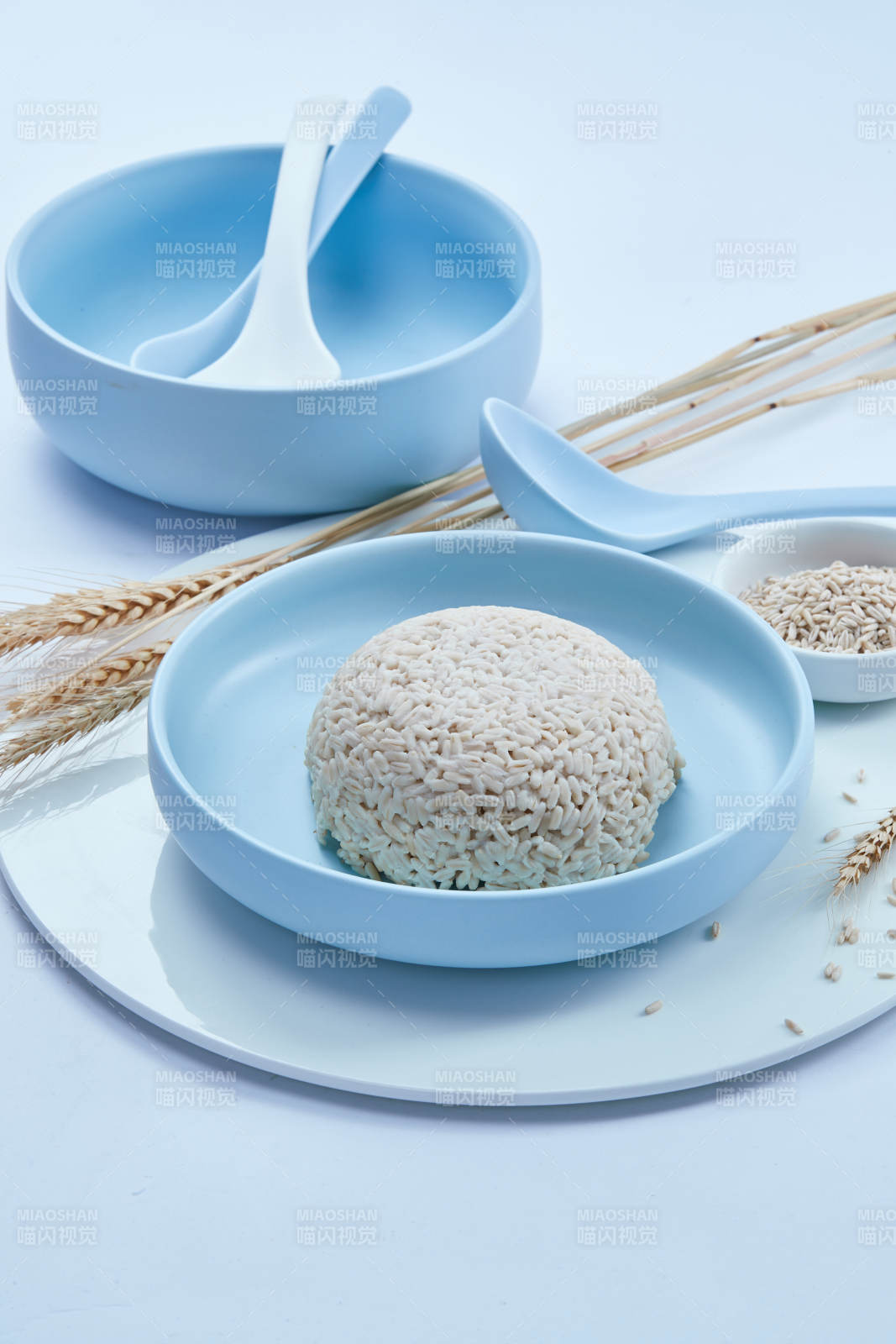 白色纸背景上的青釉瓷餐具及木质餐具装的燕麦米