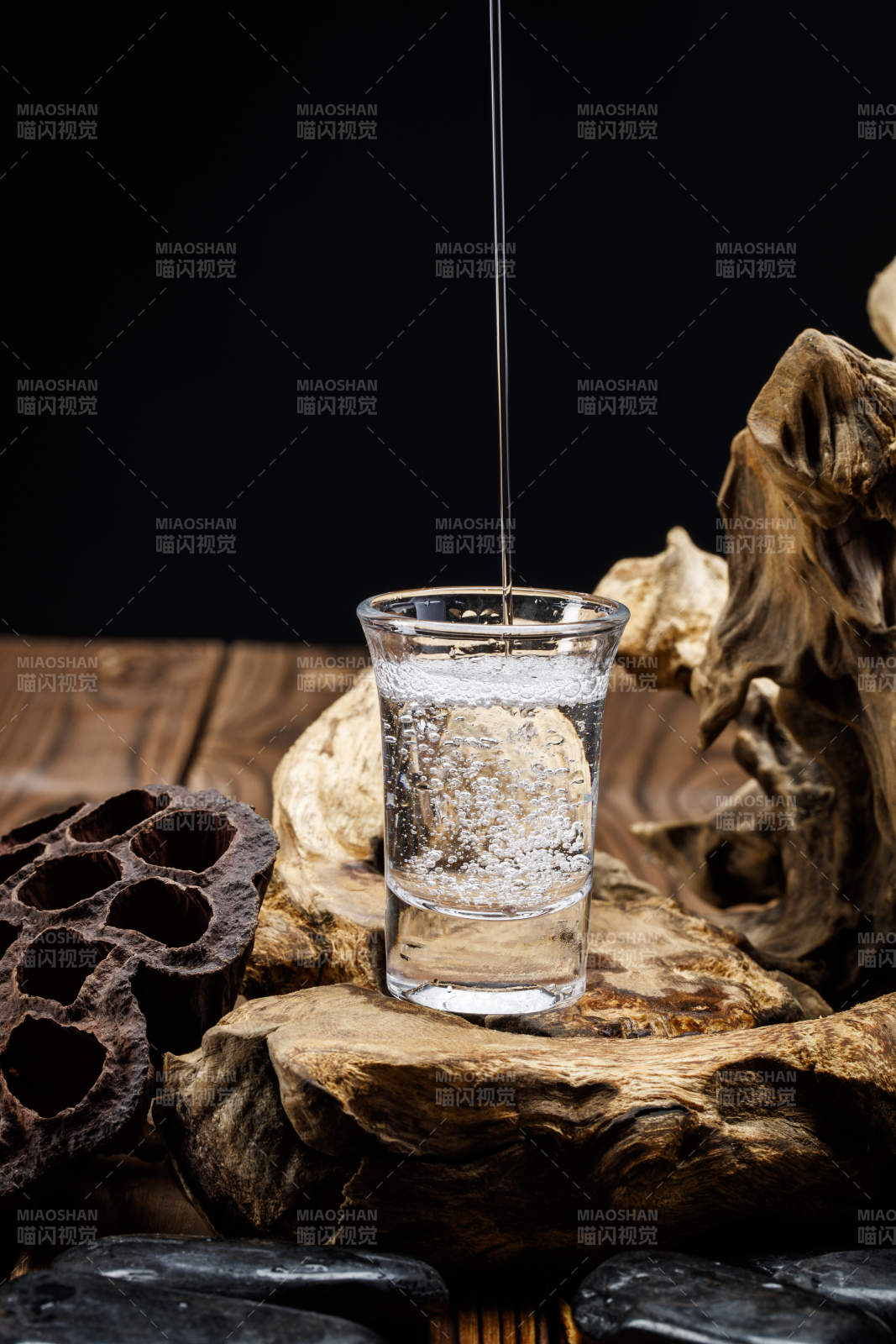 向木板上摆放的酒具内倒入清澈的白酒激起无数酒花