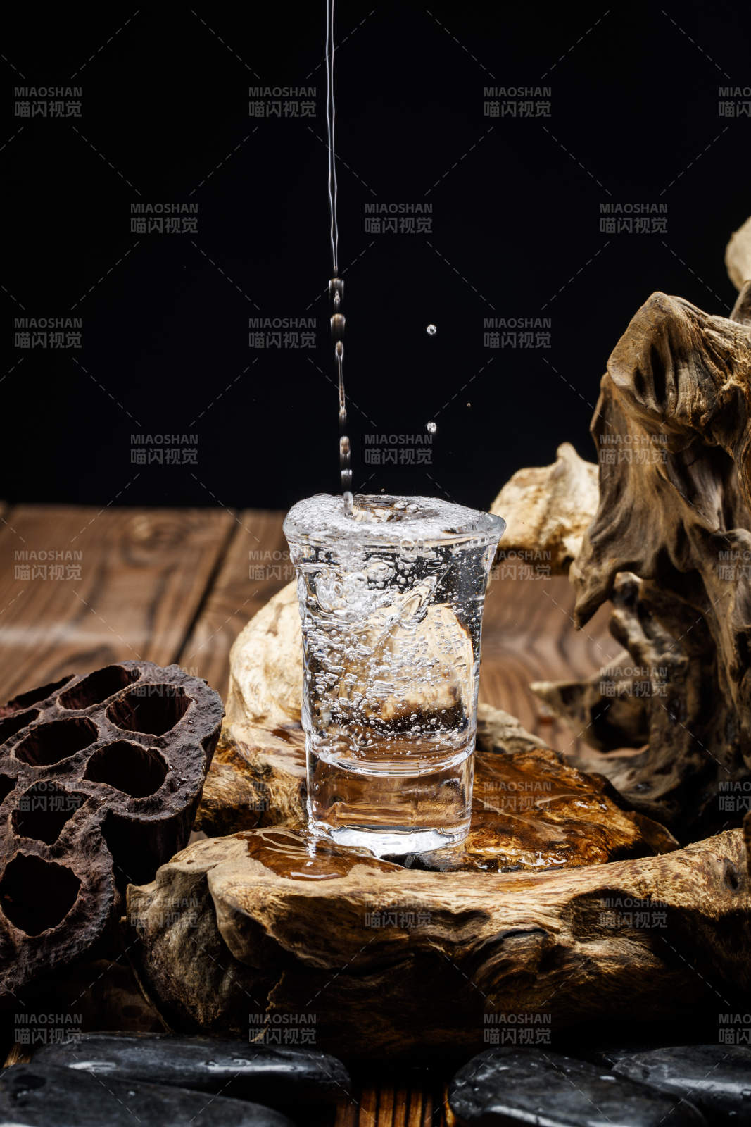 向木板上摆放的酒具内倒入清澈的白酒激起无数酒花