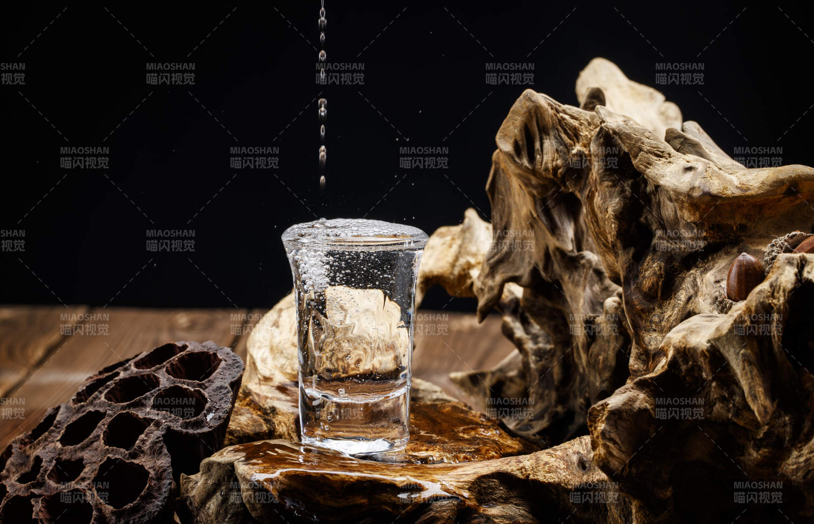 向木板上摆放的酒具内倒入清澈的白酒激起无数酒花