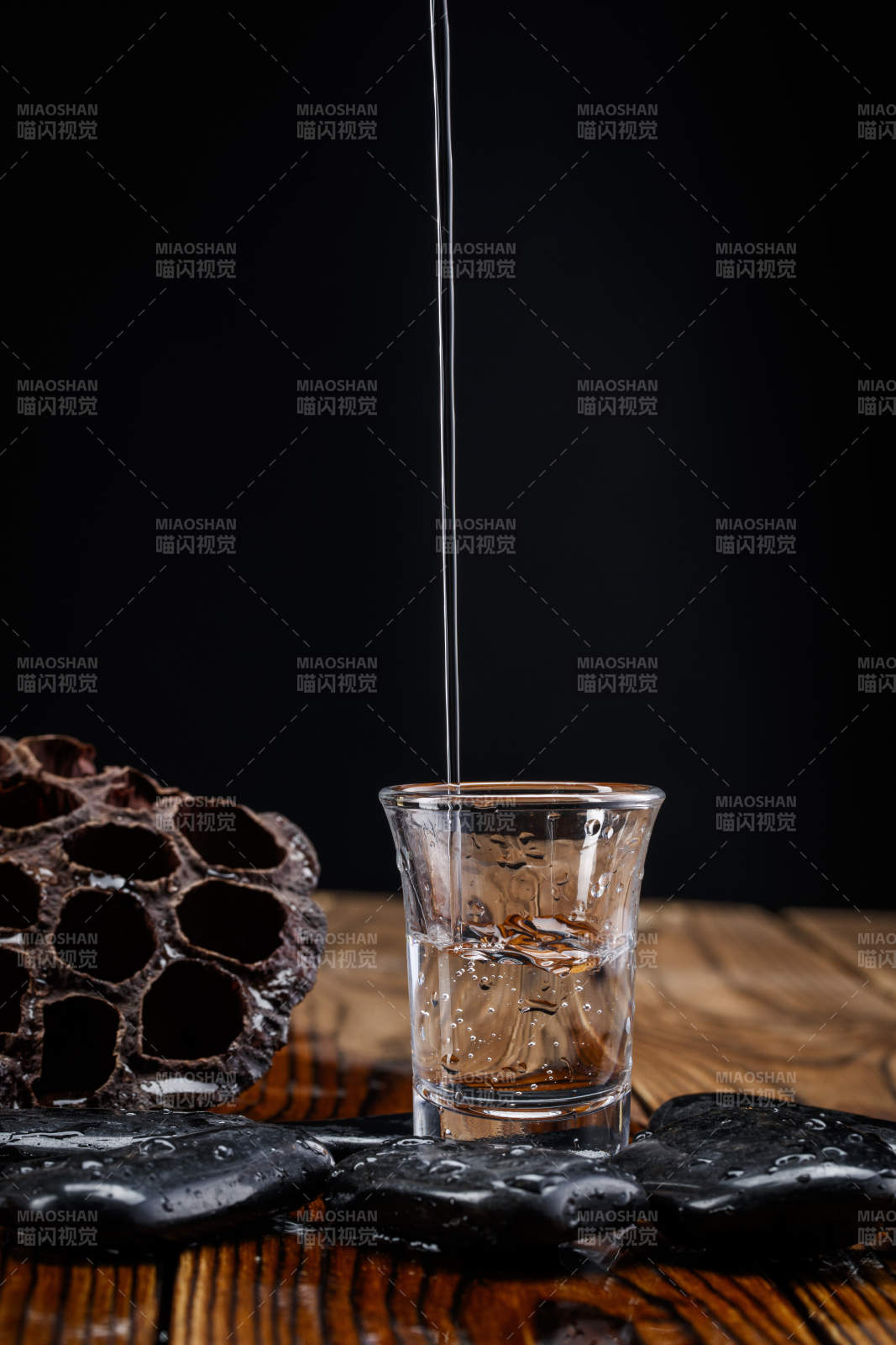 向木板上摆放的酒具内倒入清澈的白酒激起无数酒花