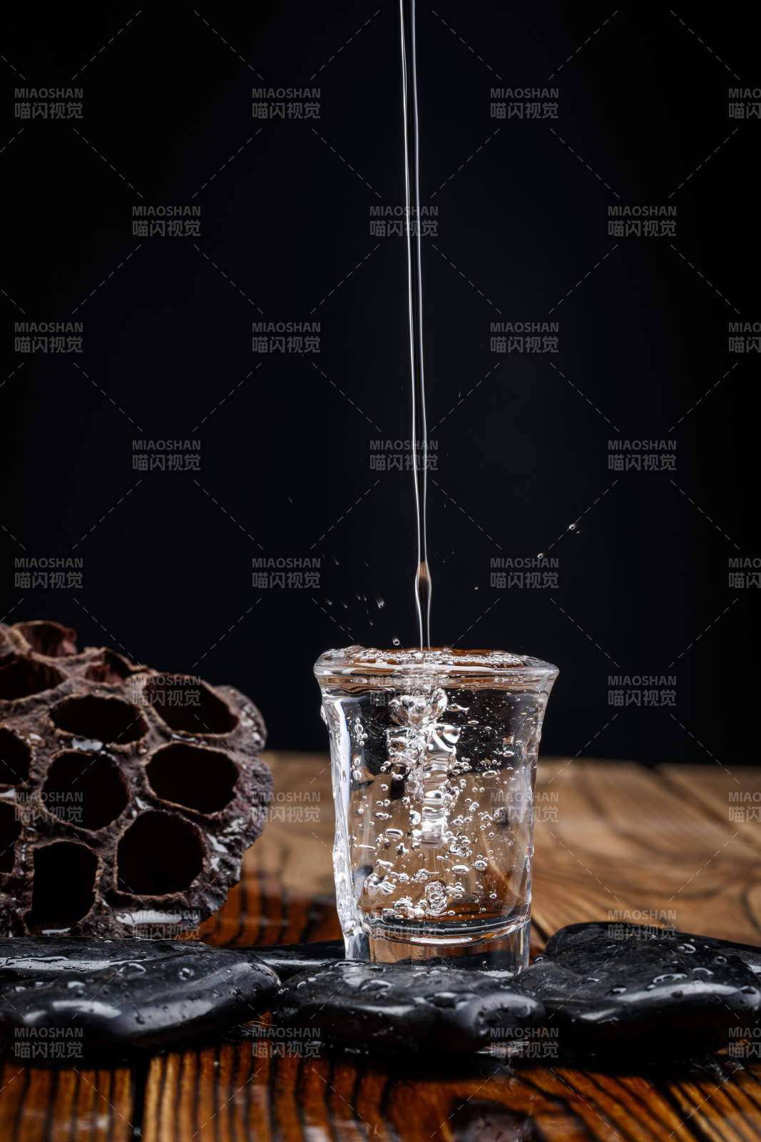 向木板上摆放的酒具内倒入清澈的白酒激起无数酒花