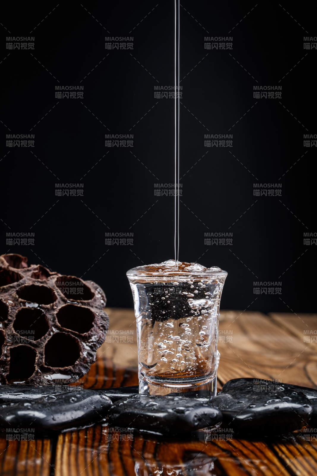 向木板上摆放的酒具内倒入清澈的白酒激起无数酒花