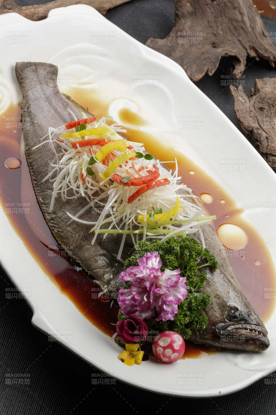 白色瓷盘装的浇汁清蒸海鲈鱼