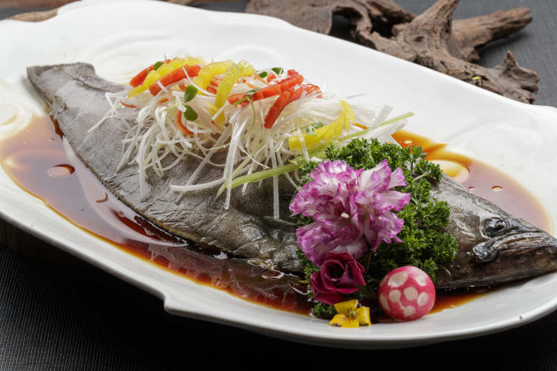 白色瓷盘装的浇汁清蒸海鲈鱼