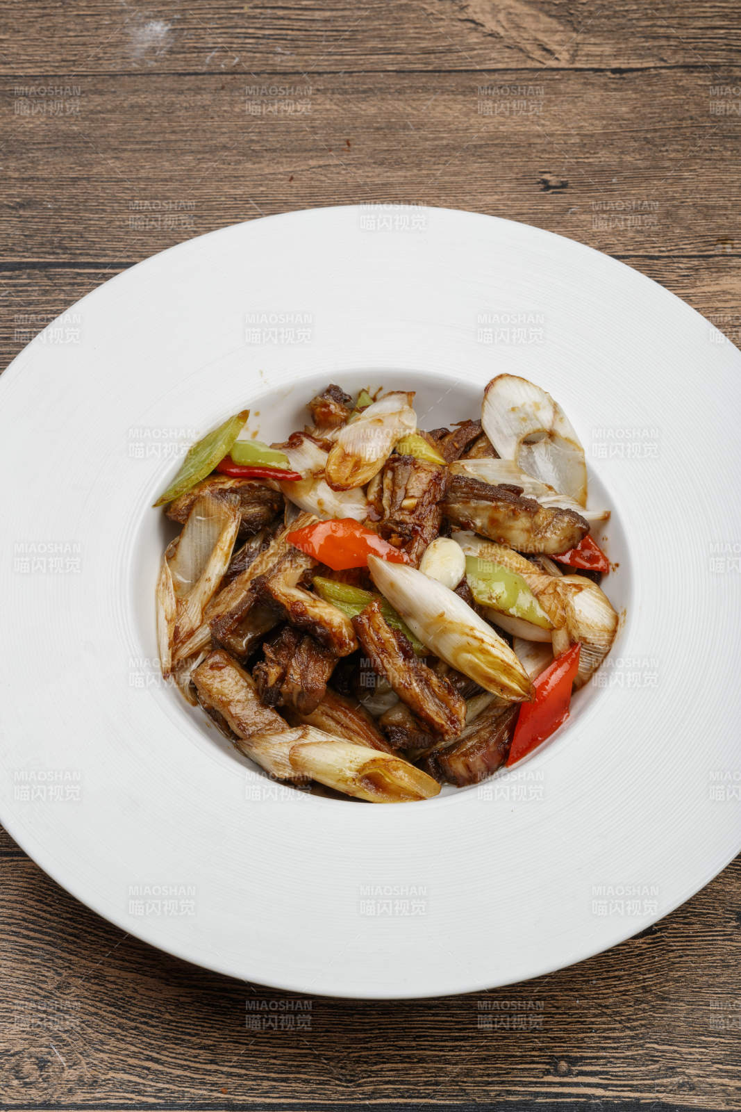 白色瓷盘装的葱爆羊五花肉