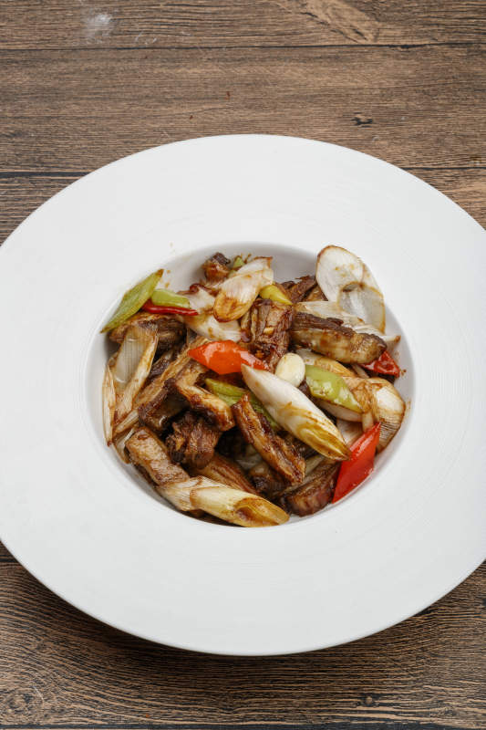 白色瓷盘装的葱爆羊五花肉