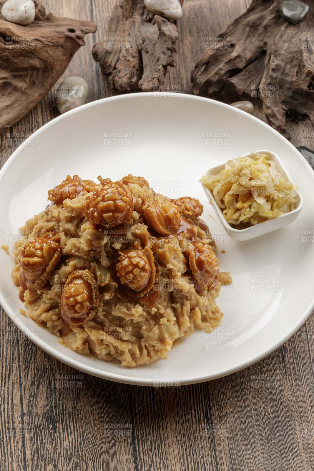 白色圓盤裝的土豆?fàn)F鮑魚擺放在樟木砧板上