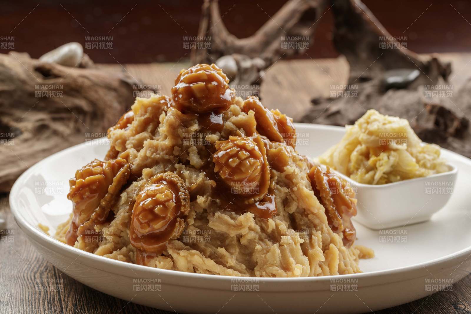 白色圆盘装的土豆焖鲍鱼摆放在樟木砧板上