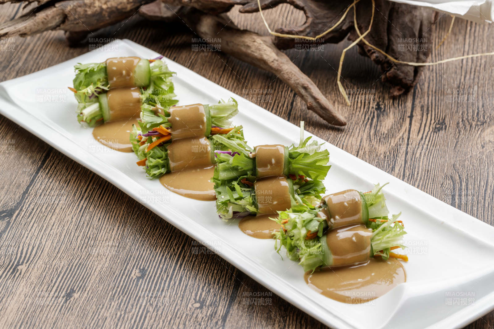 白色瓷盘装的芝麻酱乳瓜卷苦菊-摄影图