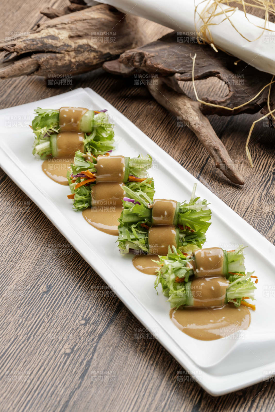 白色瓷盘装的芝麻酱乳瓜卷苦菊-摄影图