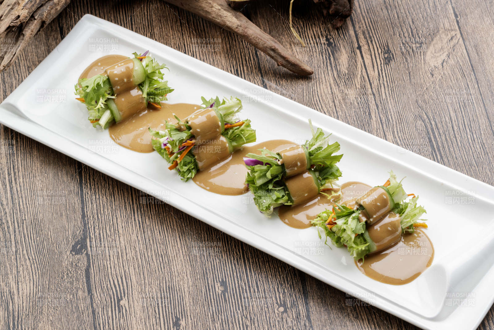 白色瓷盘装的芝麻酱乳瓜卷苦菊-摄影图