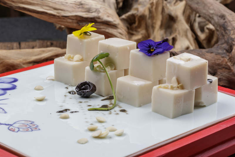 圆形黑色石盘装的奶香杏仁糕摆放在寿司帘上