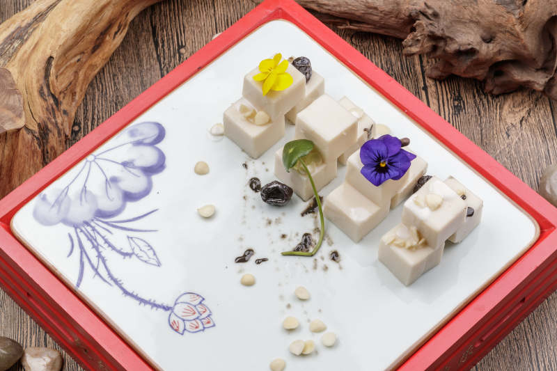 圆形黑色石盘装的奶香杏仁糕摆放在寿司帘上