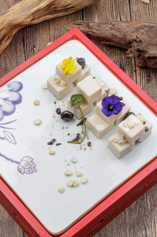 圆形黑色石盘装的奶香杏仁糕摆放在寿司帘上