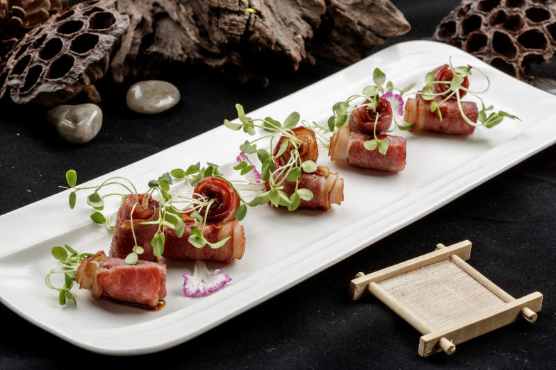 白色瓷盘装的香椿苗培根卷