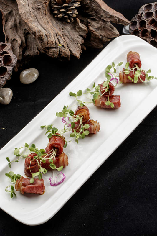 白色瓷盘装的香椿苗培根卷