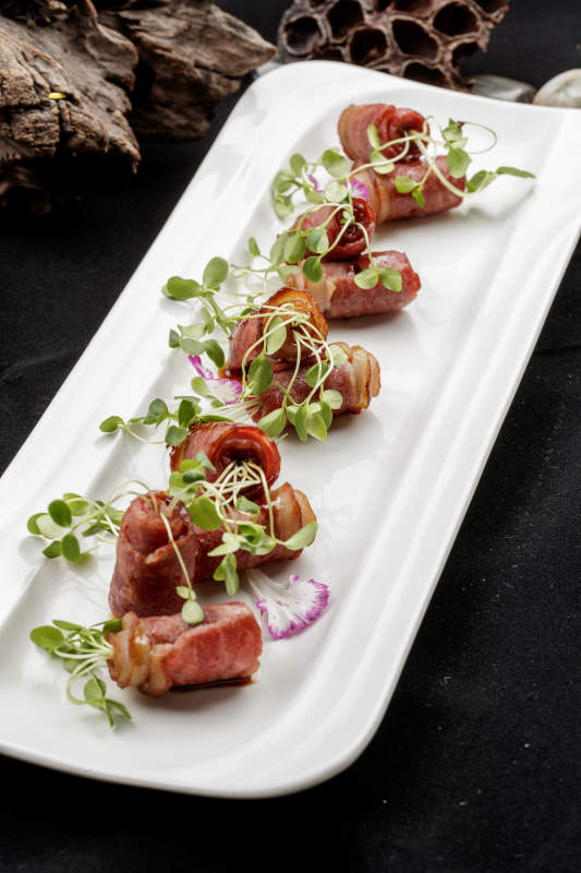 白色瓷盘装的香椿苗培根卷