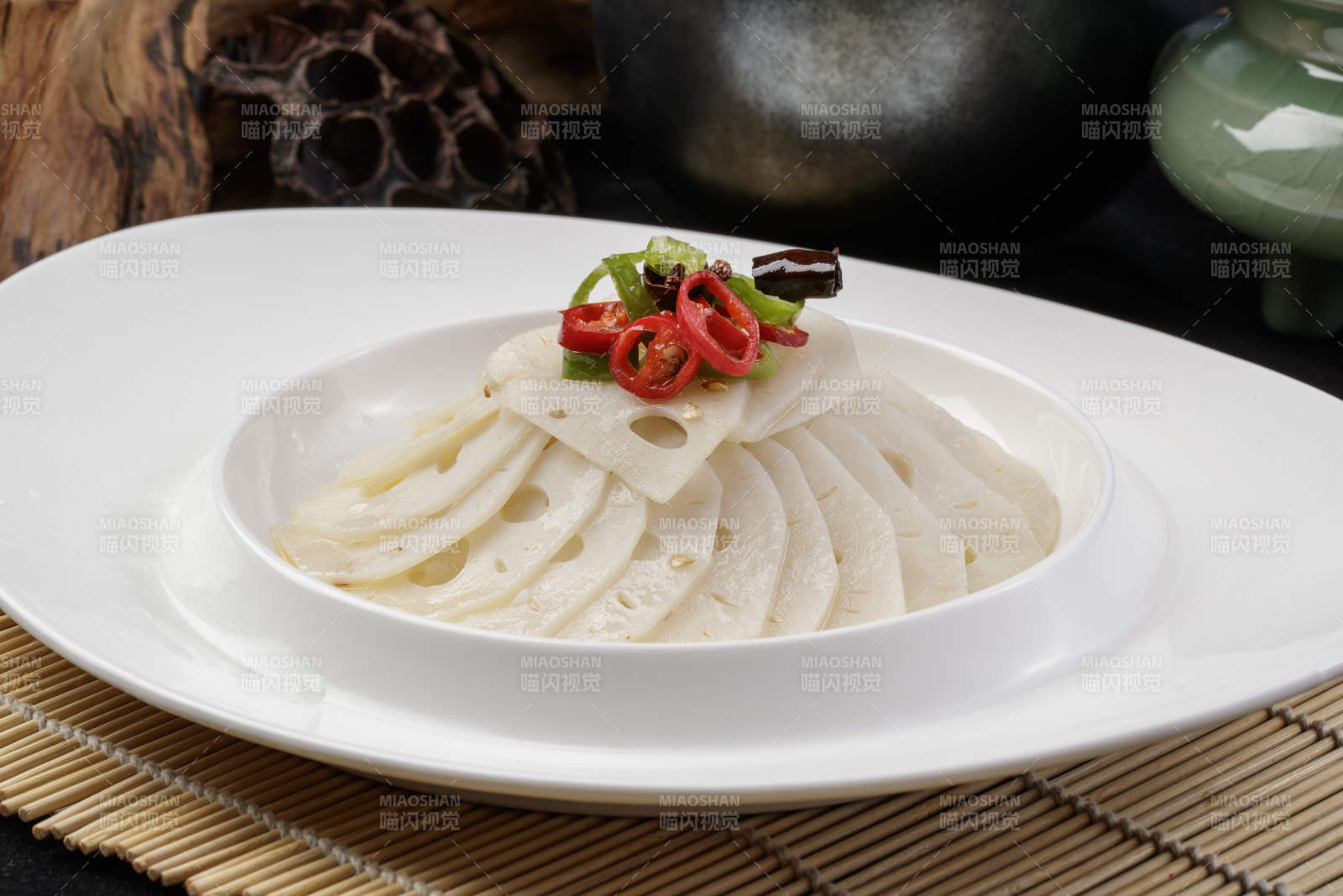 椭圆瓷盘装的蘸汁鲜藕摆放在寿司帘上