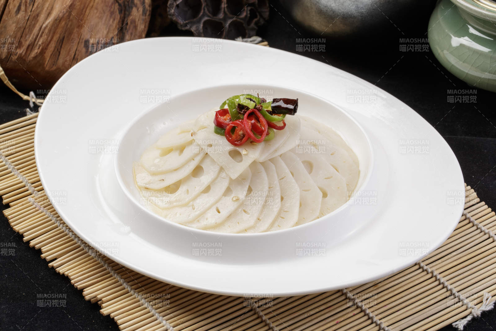 椭圆瓷盘装的蘸汁鲜藕摆放在寿司帘上