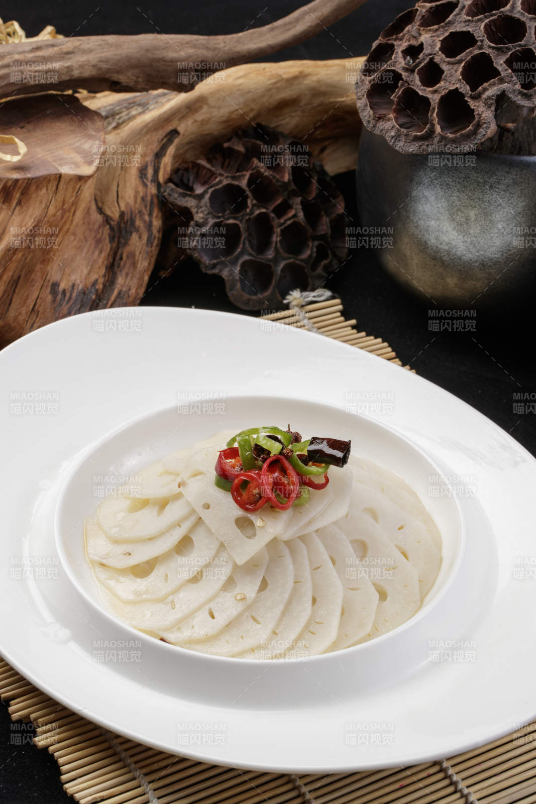 椭圆瓷盘装的蘸汁鲜藕摆放在寿司帘上