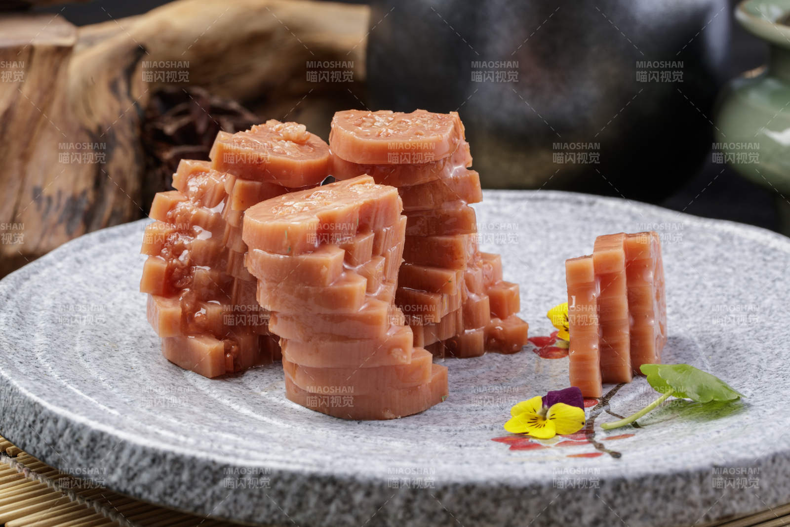 灰色螺旋瓷盘装的蜂蜜黄米藕摆放在寿司帘上