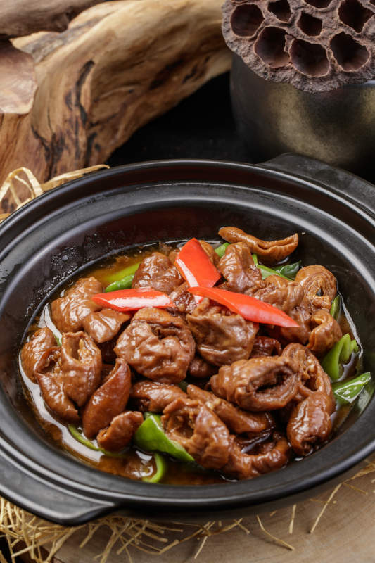 黑色砂锅装的砂锅肥肠摆放在麻布垫子上