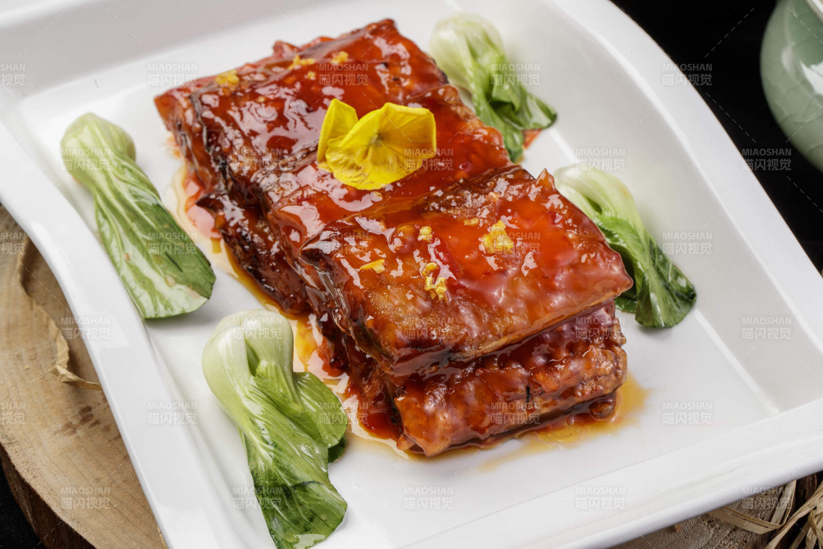 长方形瓷盘装的红烧带鱼段摆放在樟木砧板上图片