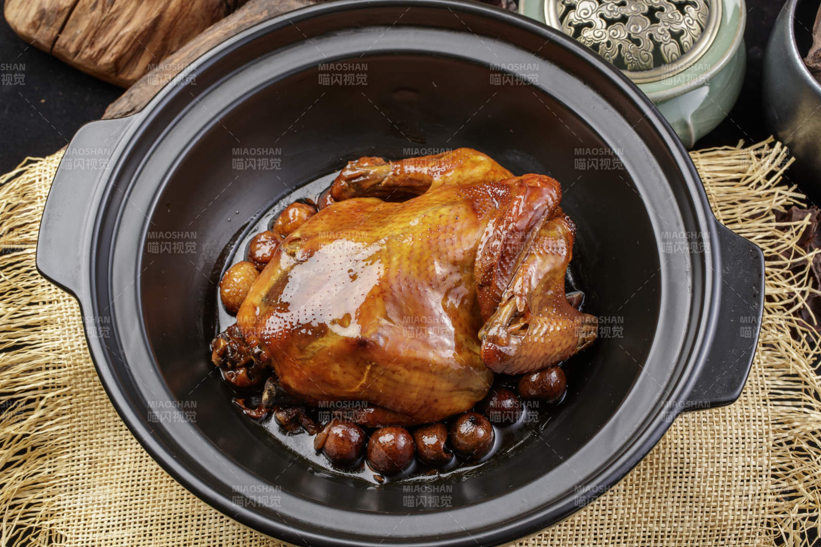 黑色砂锅装的板栗鸡摆放在麻布垫子上