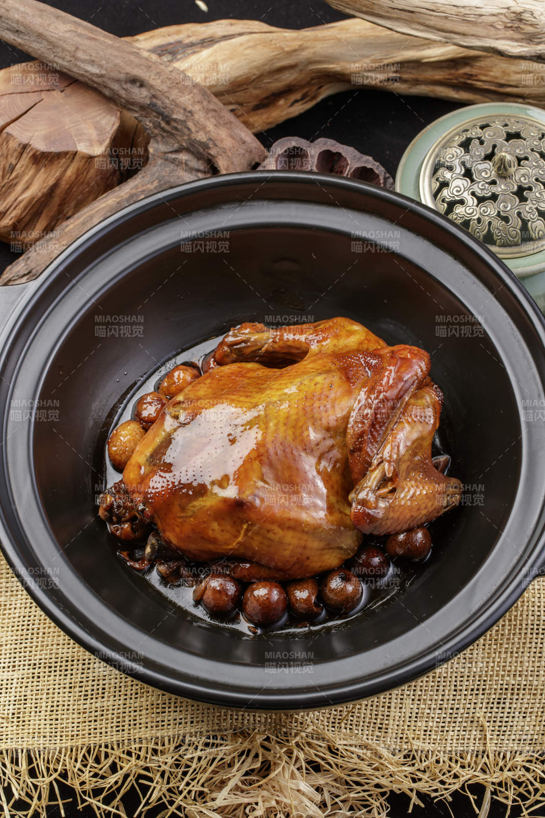 黑色砂锅装的板栗鸡摆放在麻布垫子上
