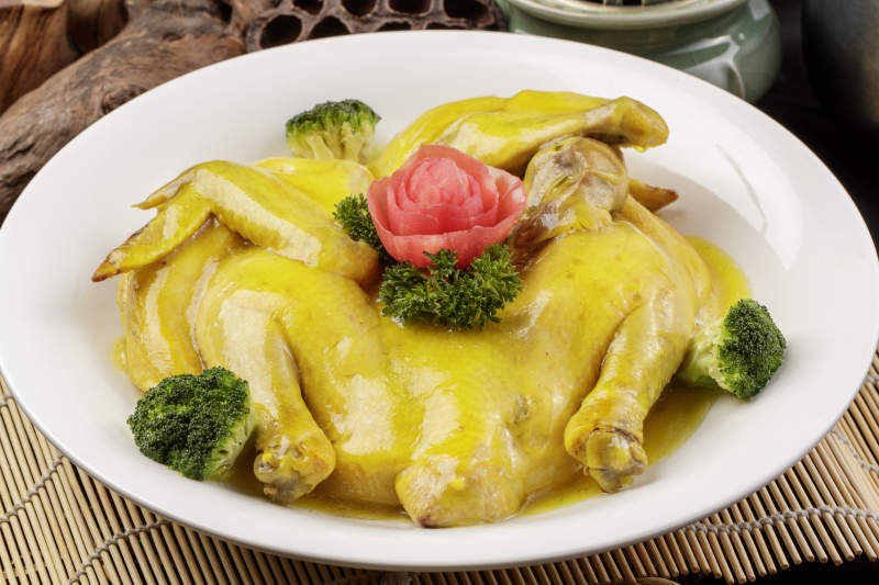 圆形瓷盘装的清蒸三黄鸡摆放在寿司帘上