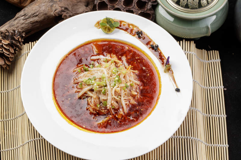 圆形瓷盘装的红油肚丝摆放在寿司帘上