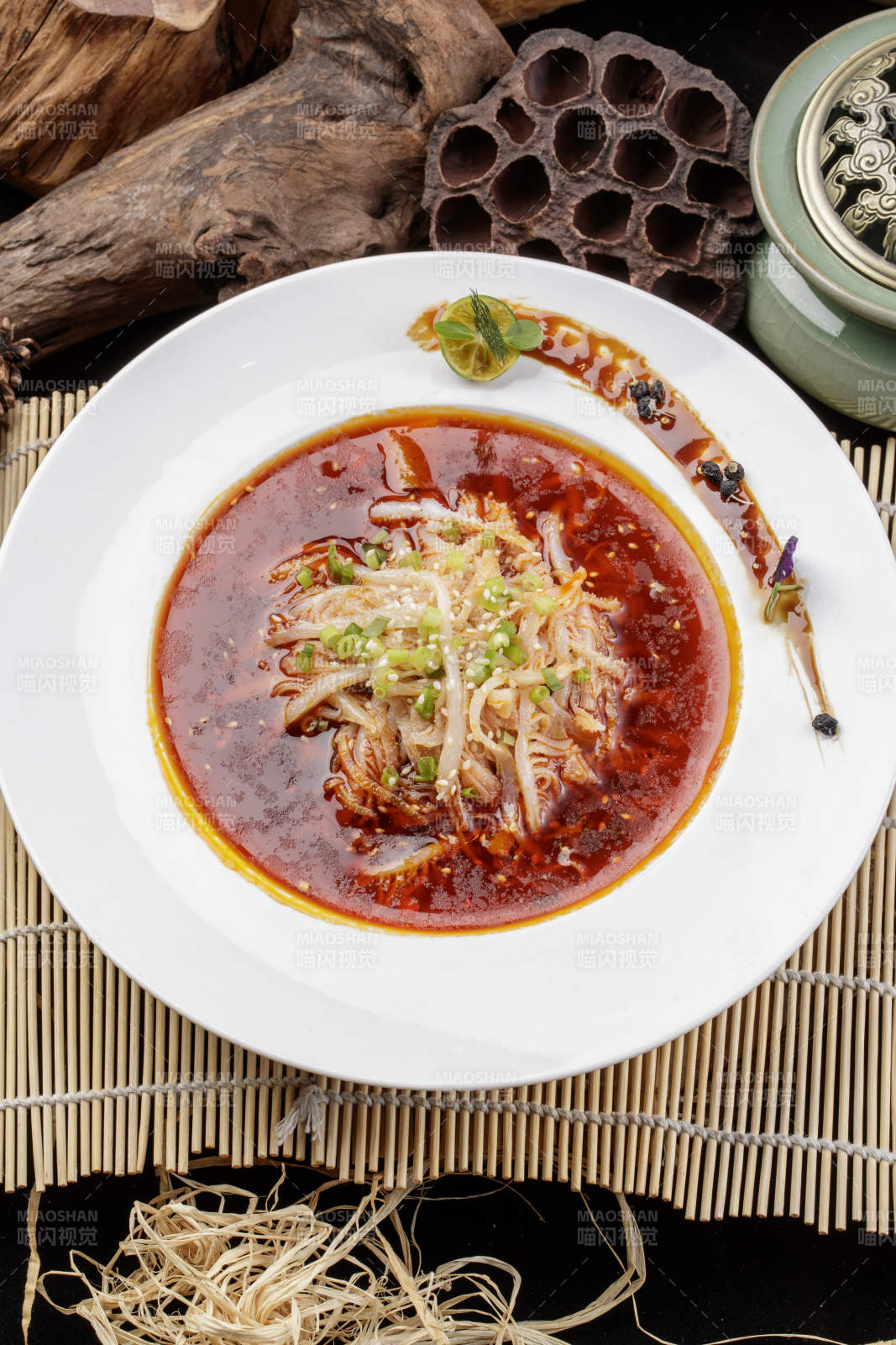 圆形瓷盘装的红油肚丝摆放在寿司帘上