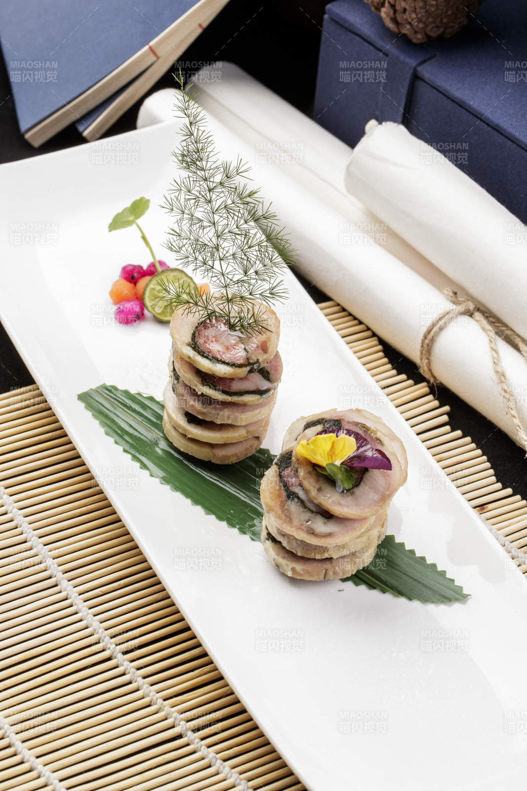 长方形瓷盘装的猪肉海苔香肠卷摆放在寿司帘上图片