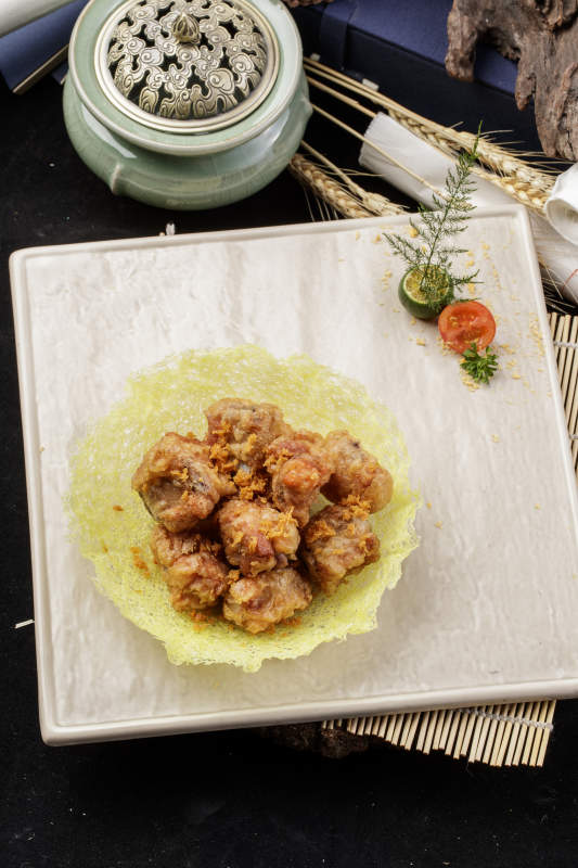 米色放瓷盤裝的金盞豬小排擺放在壽司簾上