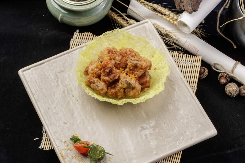 米色放瓷盤裝的金盞豬小排擺放在壽司簾上