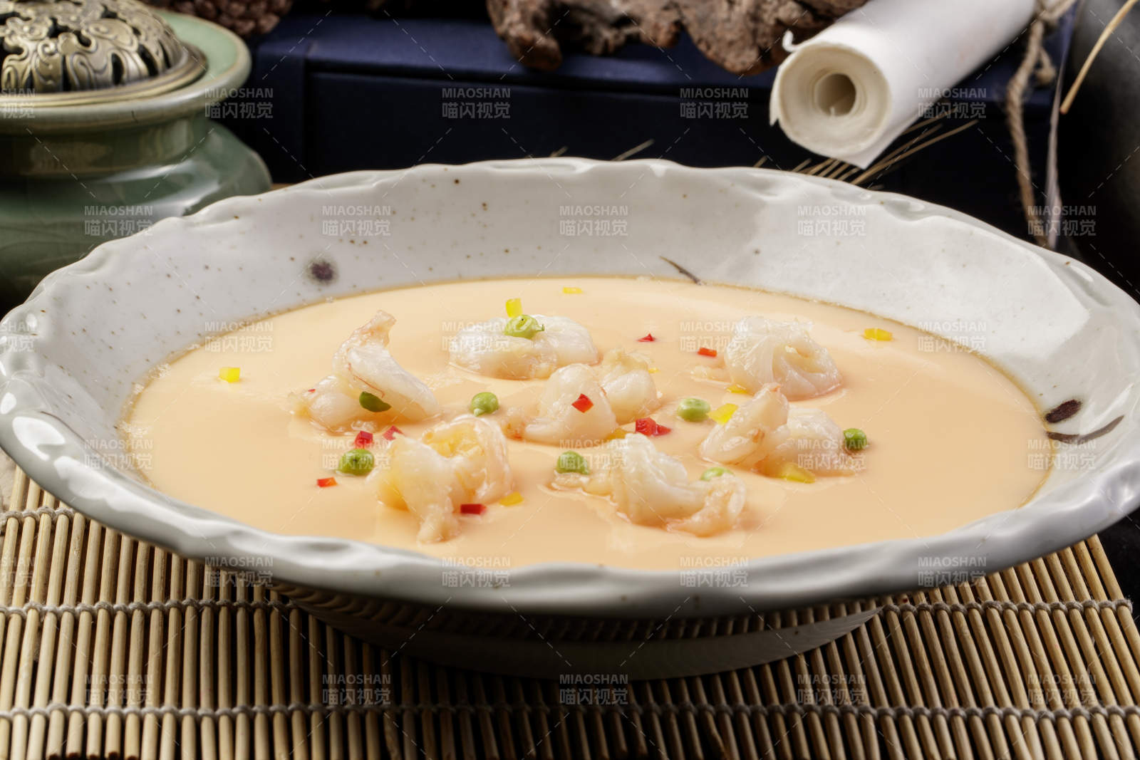 米色圓盤裝的蝦仁蒸水蛋擺放在壽司簾上